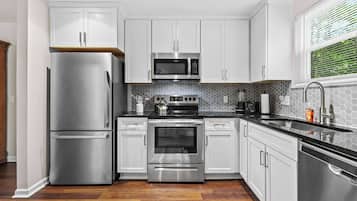 A modern kitchen with stainless steel appliances, white cabinetry, and a black countertop.