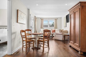 A room with a dining table, chairs, a sofa, and a cabinet.