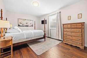 Ein Schlafzimmer mit Bett, Kommode und einem Bild an der Wand.