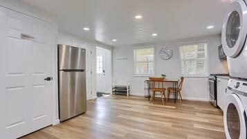 Eine Küche mit Edelstahlkühlschrank, Waschmaschine und Essbereich mit Tisch und Stühlen.