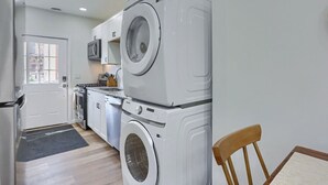 A compact kitchen with a refrigerator, microwave, stove, and stacked washing machines. - Pittsburgh, Millvale Stylish 2BD with Parking (Millvale)