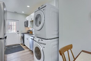 A compact kitchen with a refrigerator, microwave, stove, and stacked washing machines. - Pittsburgh, Millvale Stylish 2BD with Parking (Millvale)