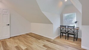 A room with a sloped ceiling, a window with blinds, a desk with two chairs, and a door. - Pittsburgh, Millvale Stylish 2BD with Parking (Millvale)