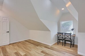 A room with a sloped ceiling, a window with blinds, a desk with two chairs, and a door. - Pittsburgh, Millvale Stylish 2BD with Parking (Millvale)