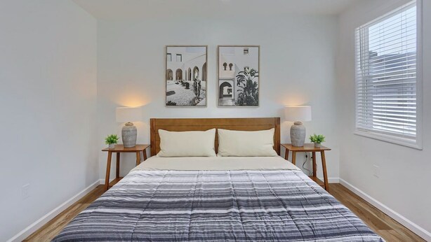 A bedroom with a bed, two bedside tables, two wall-mounted lamps, and two framed pictures. - Pittsburgh, Millvale Stylish 2BD with Parking (Millvale)