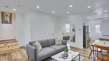 A modern living room with a grey sofa, a coffee table, and a dining area with wooden chairs.