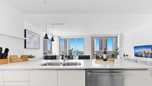 A modern kitchen with a large island, stainless steel appliances, and a city view through large windows. - New! 3 BDR Condo Pool Gym - Private Balcony (Hallandale Beach)