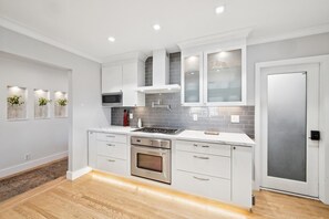 A modern kitchen with white cabinetry, a stainless steel oven, a microwave, and a gas stove. - Penthouse Views without the lower floors (Oakland)