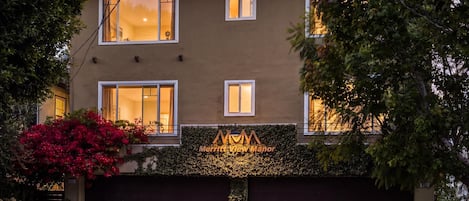 Un bâtiment à deux étages avec une porte de garage de couleur sombre, une enseigne indiquant « Merritt View Manor », et un espace paysager agrémenté de fleurs rouges.