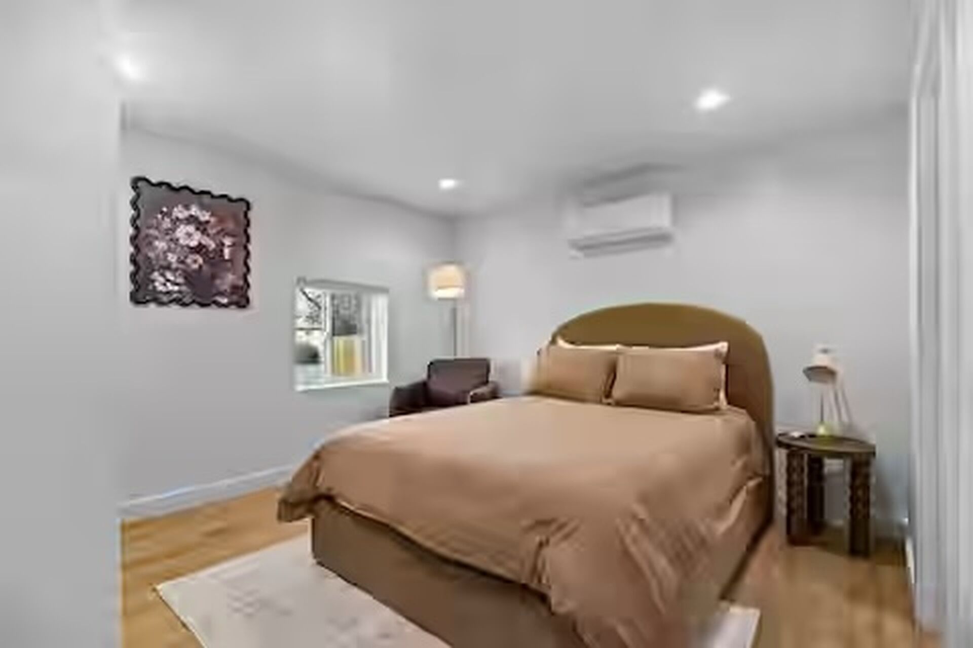 A bedroom with a bed, bedside table, lamp, and a window.