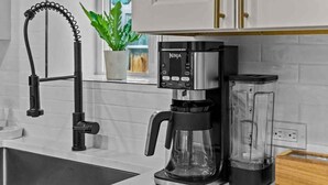 Une cuisine équipée d’une machine à café, d’un mixeur et d’un robinet moderne.