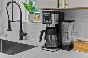 A kitchen with a coffee maker, a blender, and a modern faucet.
