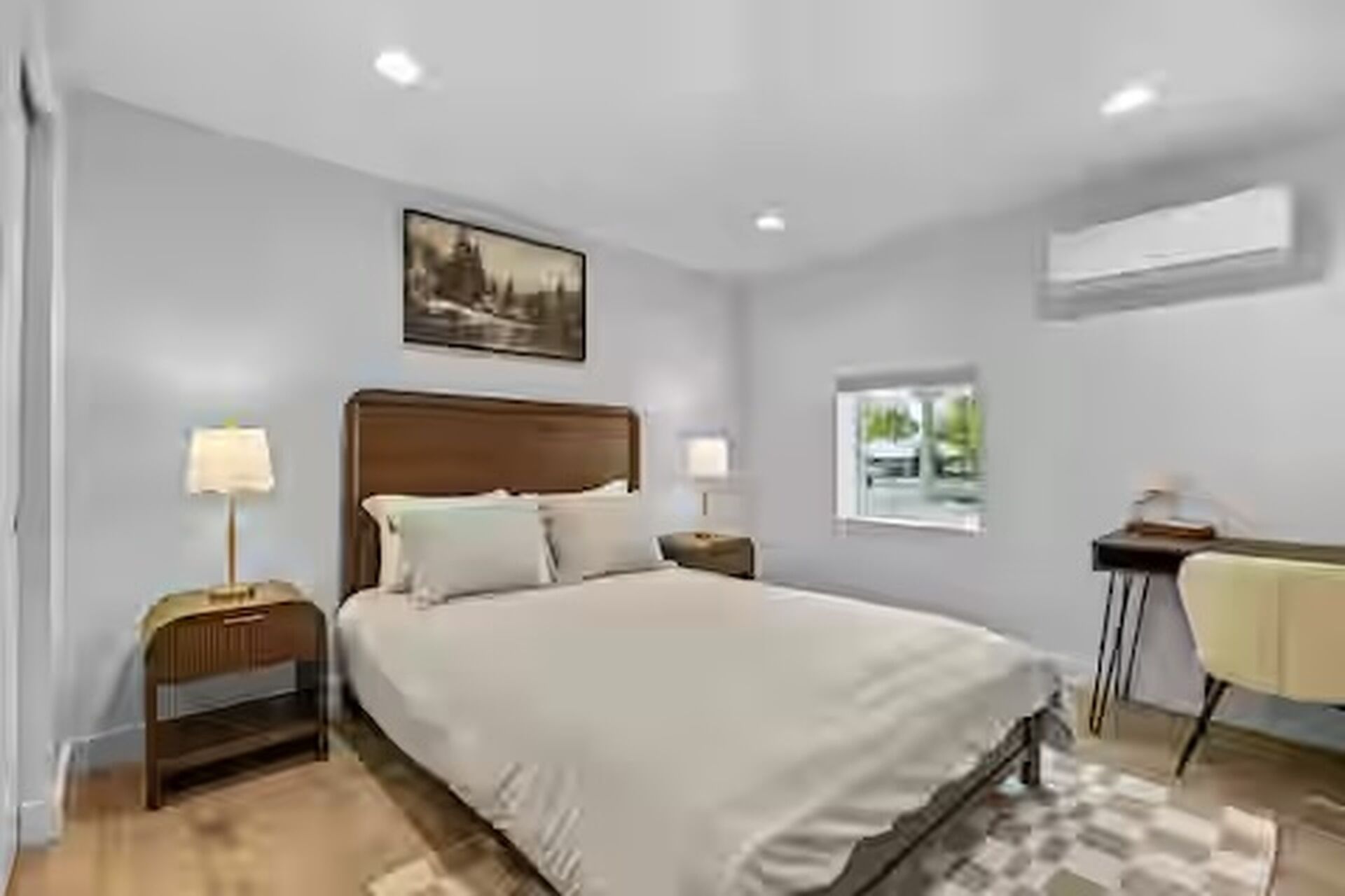 A bedroom with a bed, bedside tables, a desk, and a window.