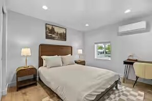 A bedroom with a bed, bedside tables, a desk, and a window.