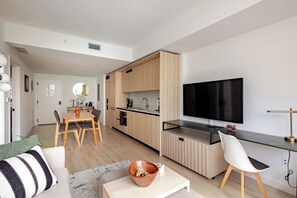 Een moderne keuken met een flatscreen televisie, houten keukenkastjes en een eethoek met een tafel en stoelen.