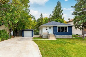 Una casa a un piano con garage, giardino anteriore e vialetto.