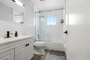 Un bagno moderno con doccia vetrata, un water bianco e un mobile lavabo con specchio.