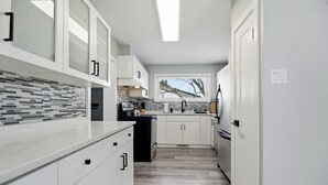Una cucina moderna con mobili bianchi, piastrelle a parete e una finestra con vista.