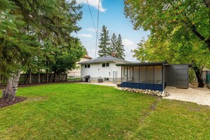 A house with a backyard, a covered patio, and a garage. - Comfortable East St. Paul Home | 3 Bed | 1 Bath | (East Saint Paul)