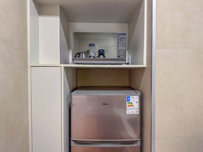 Eine Küchenzeile mit Mikrowelle, Wasserkocher und Kaffeemaschine auf der oberen Ablagefläche und einem Kühlschrank darunter.