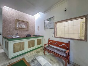 A reception area with a counter, a bench, a framed picture, a bulletin board, and a tiled window. - Copacabana: renovated, 3 min from the beach (Rio de Janeiro)