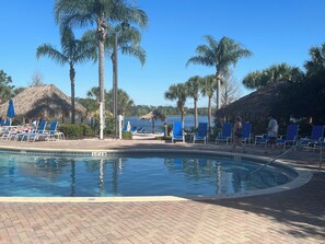 A pool area with lounge chairs, palm trees, and a clear sky.