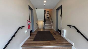 Un escalier avec un tapis sombre, des murs blancs et des rampes noires.