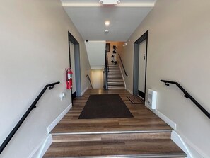 A staircase with a dark rug, white walls, and black handrails.