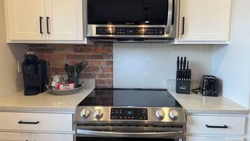 A kitchen with a stainless steel microwave, an induction cooktop, and an oven.