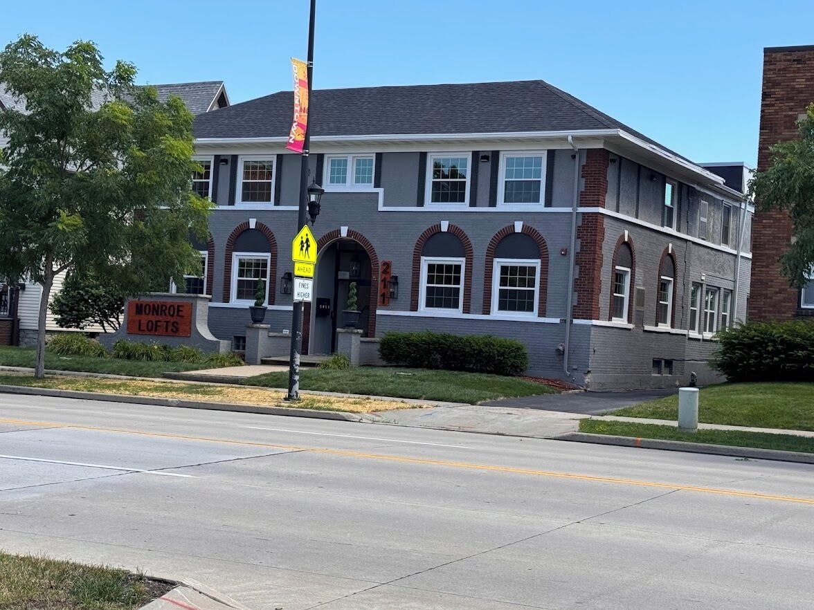 Un immeuble de deux étages avec une enseigne indiquant « Monroe Lofts » et un panneau de signalisation pour le passage des piétons.