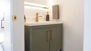 Un baño con un lavabo blanco, un espejo y un armario verde.