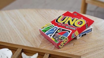 A UNO game box on a wooden table with a starfish decoration.