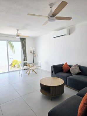 A modern living room with a sofa, a round coffee table, and a ceiling fan. - Modern Coastal Oasis with Private Pool (Puerto Morelos)
