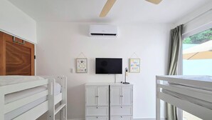Ein Zimmer mit Etagenbett, einem weißen Schrank, Deckenventilator, Flachbildfernseher und zwei Wandbildern mit Motivationssprüchen.