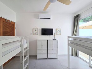 A room with a bunk bed, a white cabinet, a ceiling fan, a flat-screen TV, and two motivational posters on the wall. - Modern Coastal Oasis with Private Pool (Puerto Morelos)