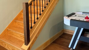 Eine Holztreppe mit schwarzen Stakobel, einem Holzgeländer und einem an der Wand befestigten Bilderrahmen.