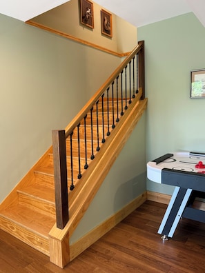 A wooden staircase with black balusters, a wooden handrail, and a wall-mounted picture frame.