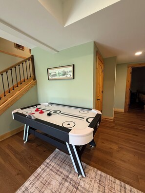 A room with a pool table, a staircase, and a framed picture on the wall.