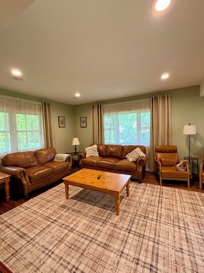 A living room with a brown leather sofa, a wooden coffee table, and a plaid rug.