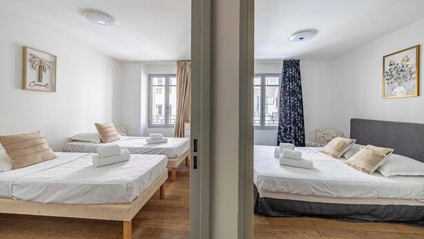 A hotel room with two beds, a window with curtains, and a framed picture on the wall. - THE PERFECT COMBINATION OF COMFORT, CONVENIENCE & A PRIME CENTRAL LOCATION. (Cannes)