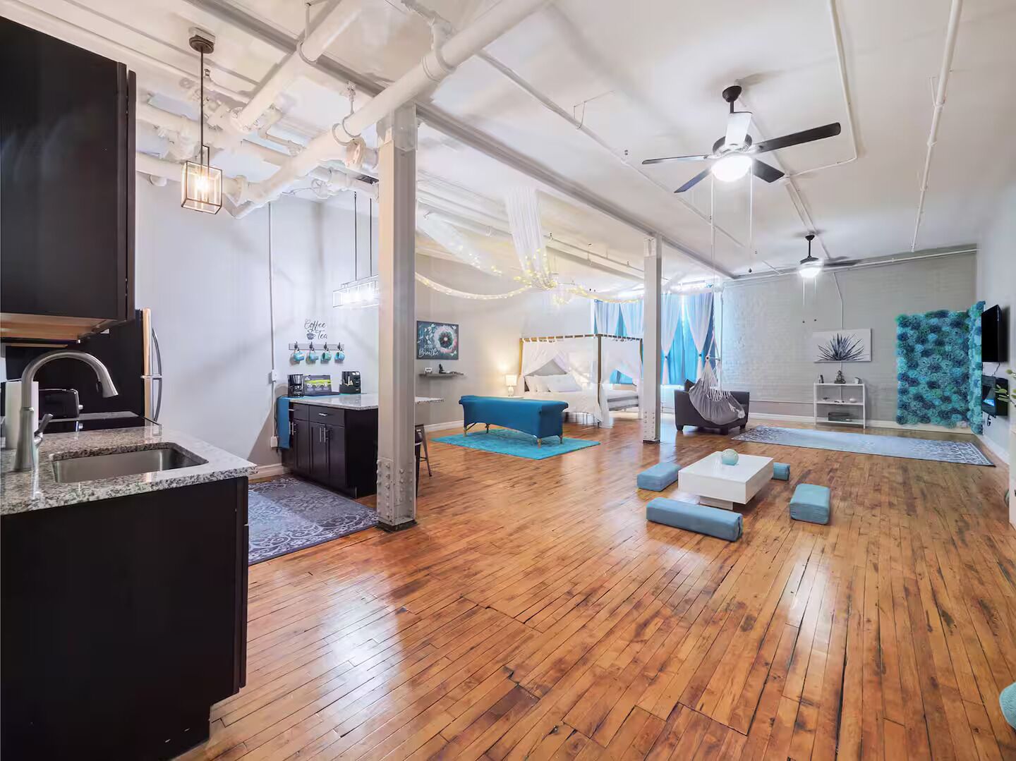 A spacious living area with a kitchen, a dining area, and a bedroom with a canopy bed.