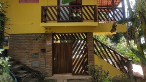 Edificio amarillo con balcón, una puerta de madera y un letrero que dice 'Residence Vila das Flores'.
