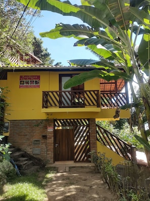 A yellow building with a balcony, a wooden gate, and a sign for 'Residence Vila das Flores'.