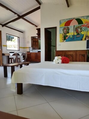 Una habitación con cama, una banca, un cuadro y vistas al exterior.