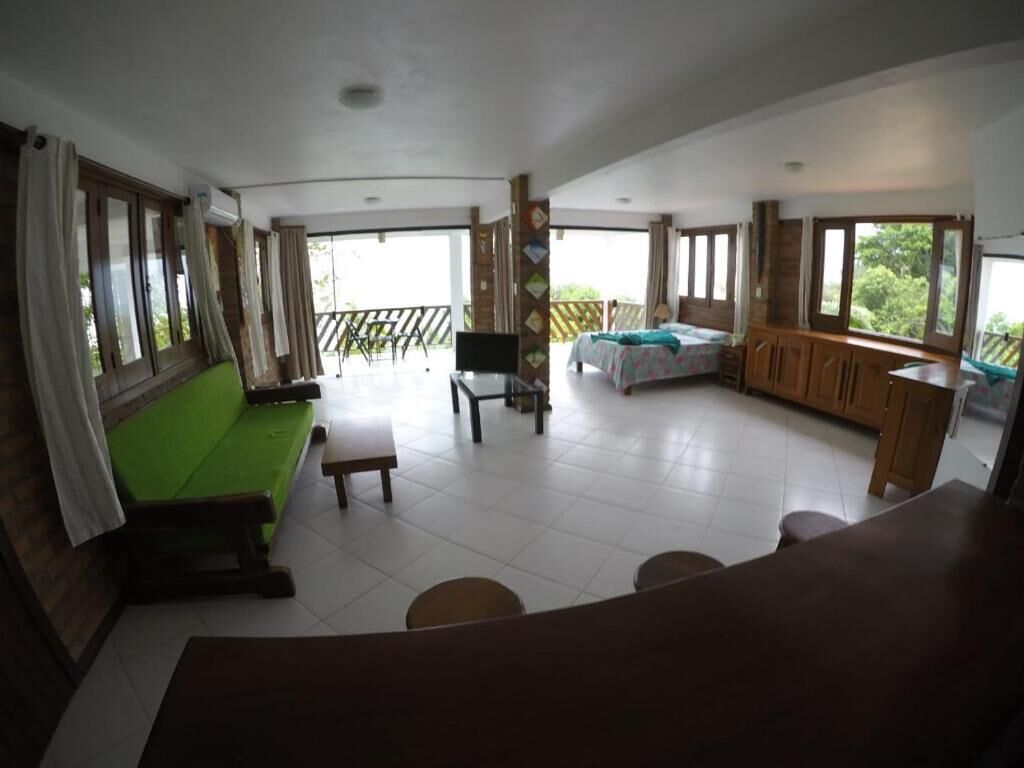 A spacious room with a green sofa, a bed, a desk, and a balcony.