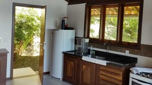 Una cocina con armarios de madera, un refrigerador, una estufa y una ventana con vistas a la vegetación.