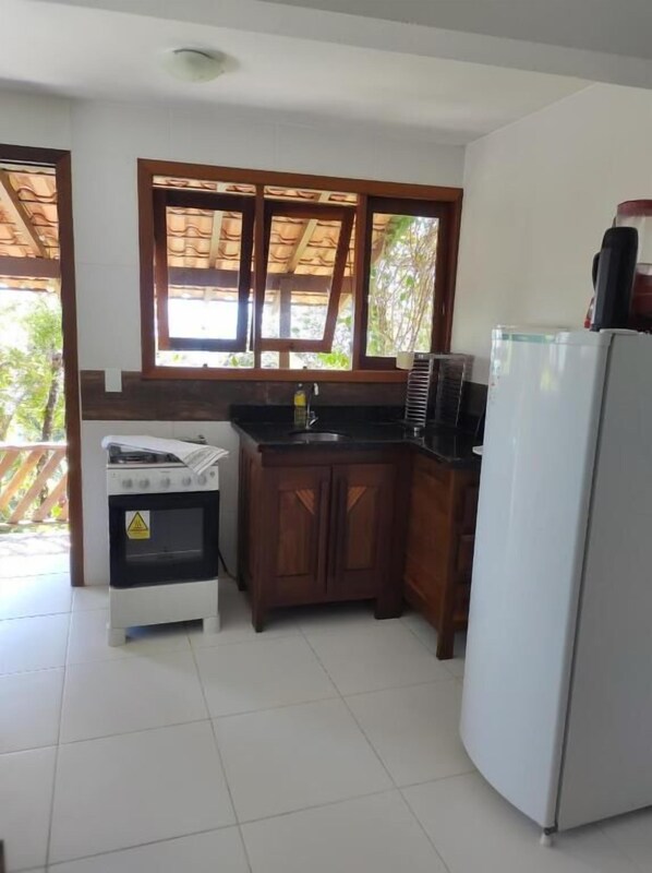 A kitchen with a stove, sink, cabinets, and a refrigerator.
