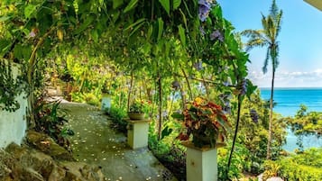 Un sendero serpentea por un jardín exuberante con vistas al océano.
