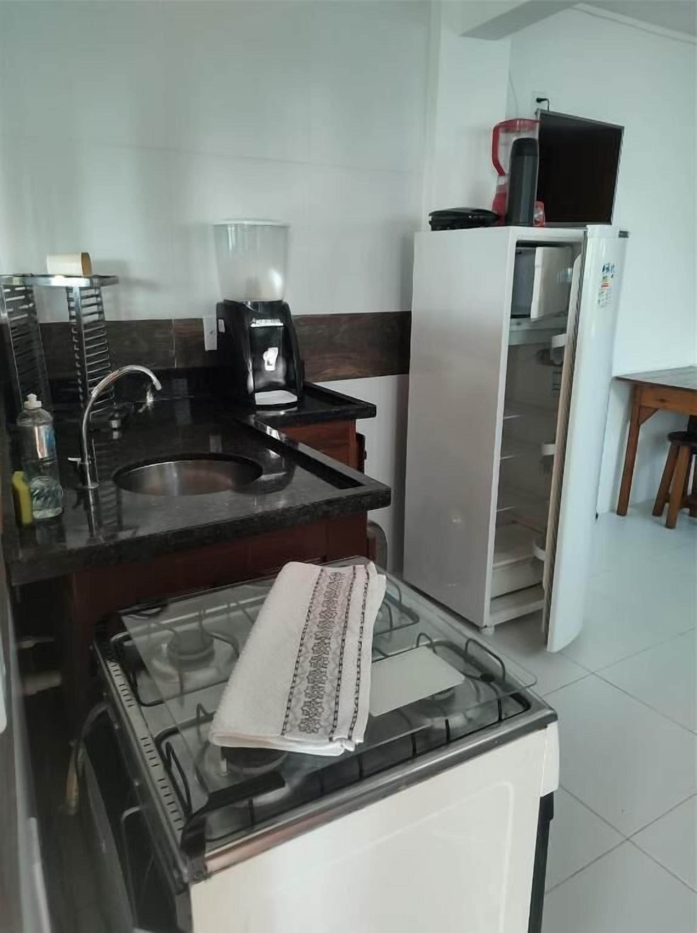 Una cocina compacta equipada con estufa a gas, cafetera y refrigerador.