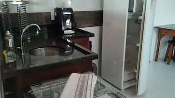 Una cocina compacta equipada con estufa a gas, cafetera y refrigerador.